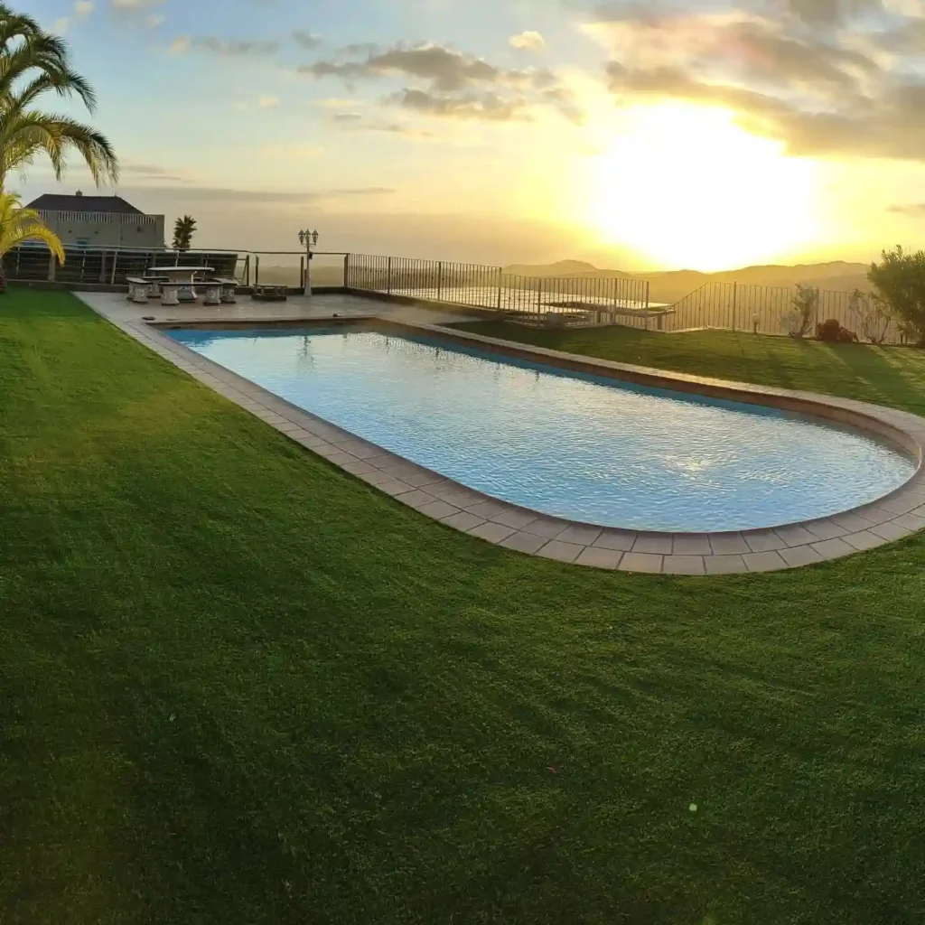 Piscina rodeada de césped artificial al atardecer