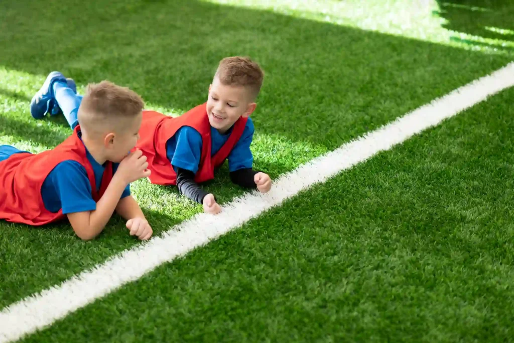 Niños tumbados sobre césped artificial en un campo deportivo