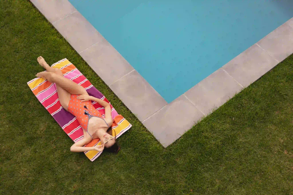chica tomando el sol en una piscina con cesped artificial adaptado para piscinas