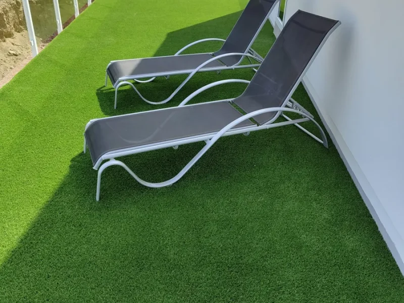 Balcón de ático con césped artificial y tumbonas instalado por Flor And Design