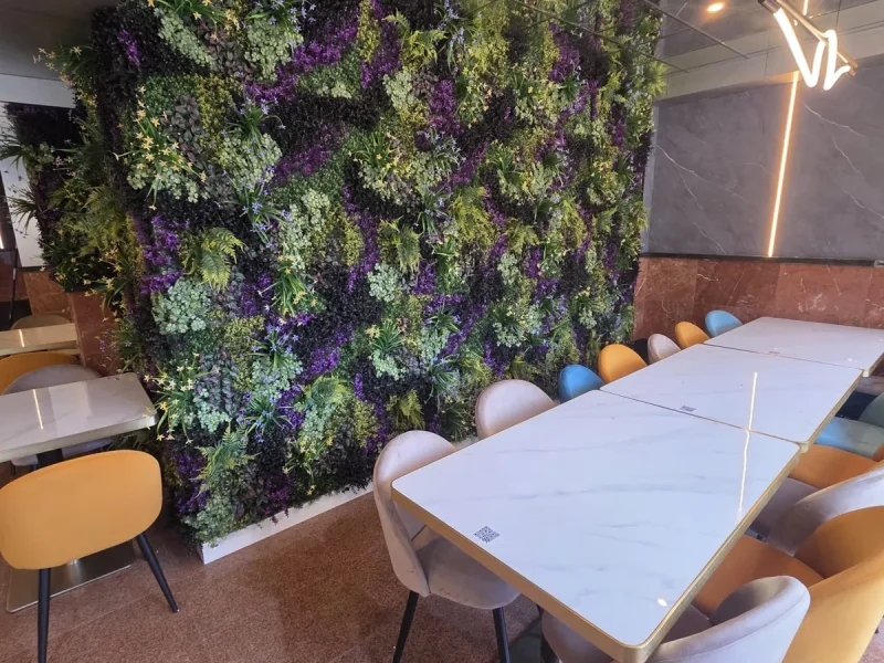 Pared de jardín vertical artificial con flores moradas en el salón de un restaurante