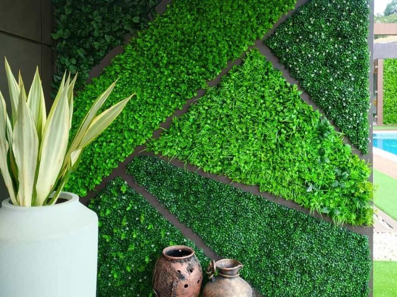 Jardín vertical artificial con formas geométricas junto a una piscina